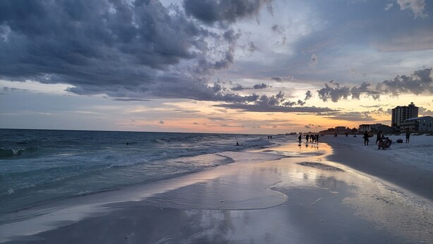 A beach with a wide sandy shore, waves, and a sunset in the background. - 948B - 4BR $700+ in freebies incl golf, Pool (Miramar Beach)