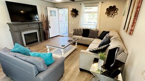 A living room with a fireplace, a sofa, a coffee table, and a TV. - Cozy 2BED 2BATH Home with central AC (Bacliff)