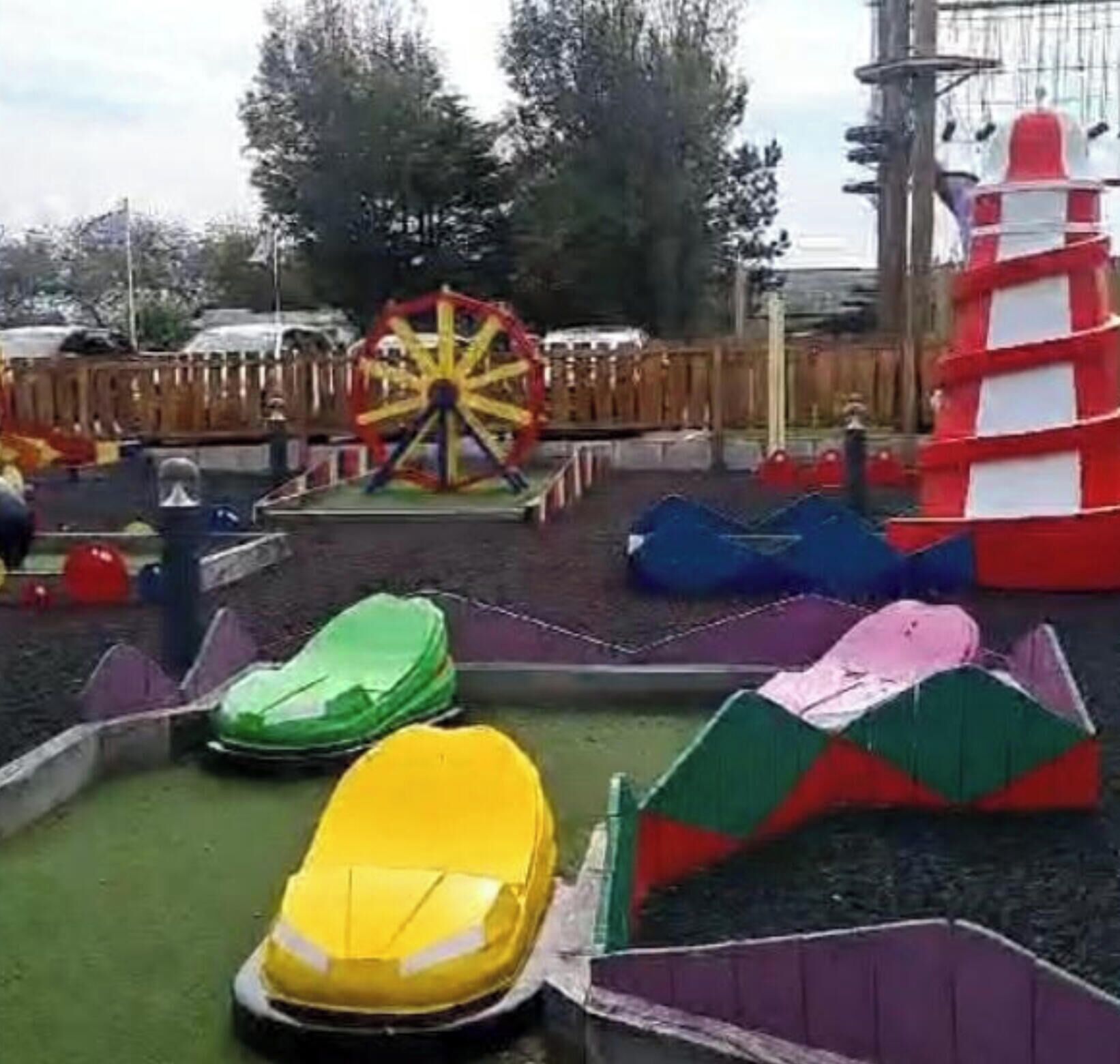 Een speelplaats met een reuzenrad, botsauto's en een klimconstructie.