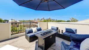 Una terrazza sul tetto con posti a sedere all'aperto, un barbecue e vista sullo skyline della città.