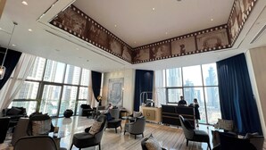 Un hall d’hôtel spacieux, doté de meubles modernes, de grandes fenêtres offrant une vue sur la ville et d’un plafond décoratif.