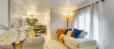 A living room with a sofa, a coffee table, a lamp, and a decorative vase with flowers.