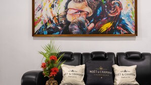 Un canapé en cuir noir agrémenté de trois coussins, dont l’un porte l’inscription « MOËT & CHANDON CHAMPAGNE ». Un vase rempli de fleurs rouges et une boîte décorative sont posés sur la table devant le canapé.
