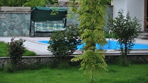 A swimming pool with a stone wall and a checkered umbrella. - Gosh Dream House (Gosh)