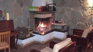 A cozy living room with a stone fireplace, wooden furniture, and a stone wall. - Gosh Dream House (Gosh)