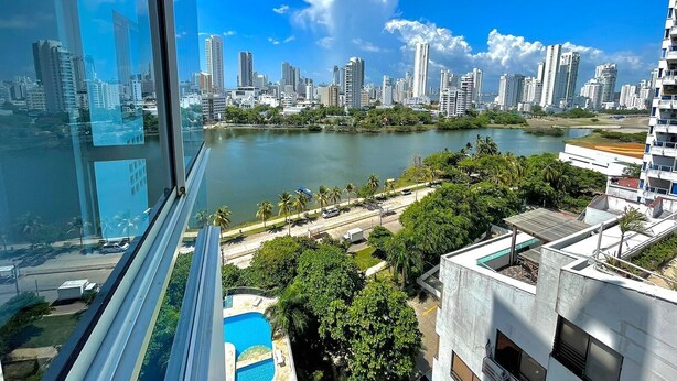 A high-rise building with a view of a city skyline, a river, and a pool area. - Estudios Mirador del Laguito (Cartagena)