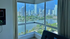 A room with a large window offering a view of a city skyline and a body of water. - Estudios Mirador del Laguito (Cartagena)