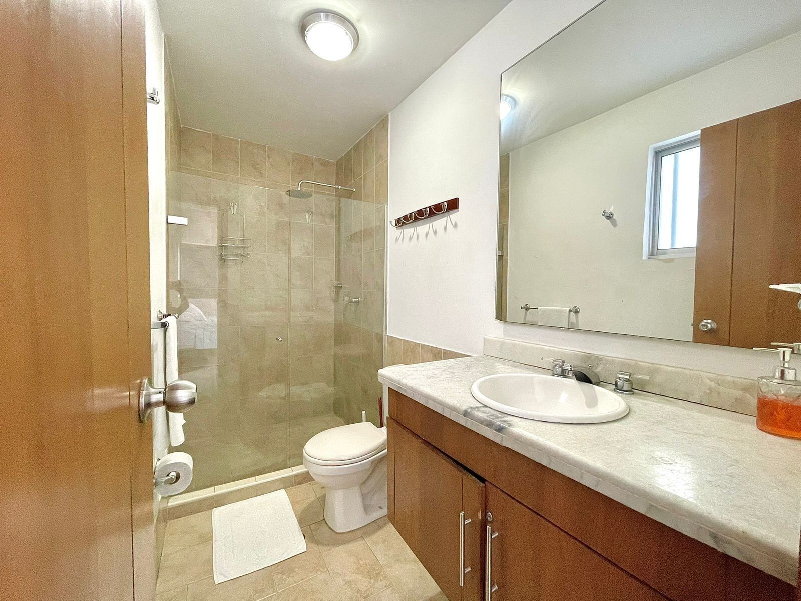 A modern bathroom with a glass shower enclosure, a toilet, a sink, and a large mirror.