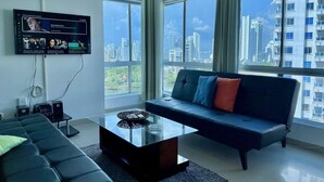 A modern living room with a large window, a flat-screen TV, and a sofa with cushions. - Estudios Mirador del Laguito (Cartagena)