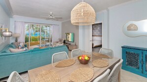 A modern living room with a teal sofa, a wooden dining table with woven placemats, and a blue cabinet.