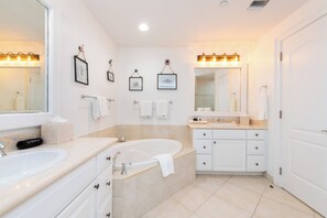 A modern bathroom with a large bathtub, two sinks, and a vanity with a mirror.