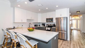 A modern kitchen with white cabinets, stainless steel appliances, and a central island with bar stools.