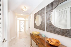 A hallway with a wooden console table, a large mirror, and a decorative tile wall.