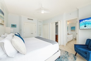 A hotel room with a bed, a ceiling fan, a TV, and a bathroom visible through an open door.