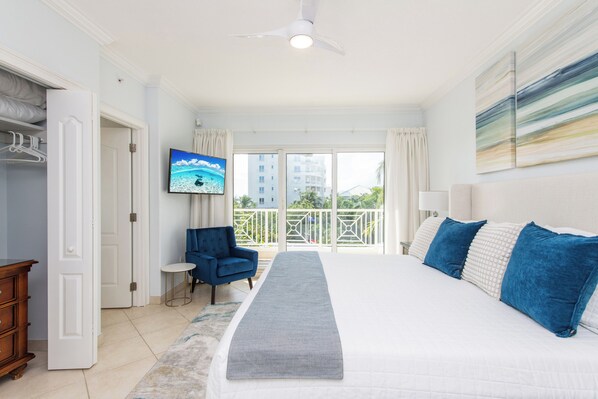 A hotel room with a bed, a television, a chair, and a view of the outside.