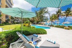 A poolside area with lounge chairs, umbrellas, and a pool.