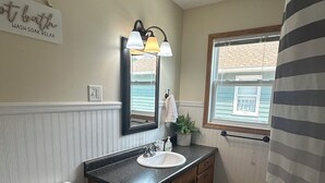 Ein Badezimmer mit Toilette, einem Waschbecken mit Spiegel darüber und einer Duschkabine.