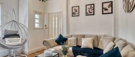 A living room with a hanging chair, a sofa, a coffee table, and wall art.