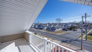 Un balcón con vistas a una calle residencial, casas y postes de servicios públicos.