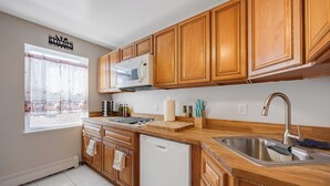 Una cocina con armarios de madera, microondas, lavavajillas y ventana con vistas.