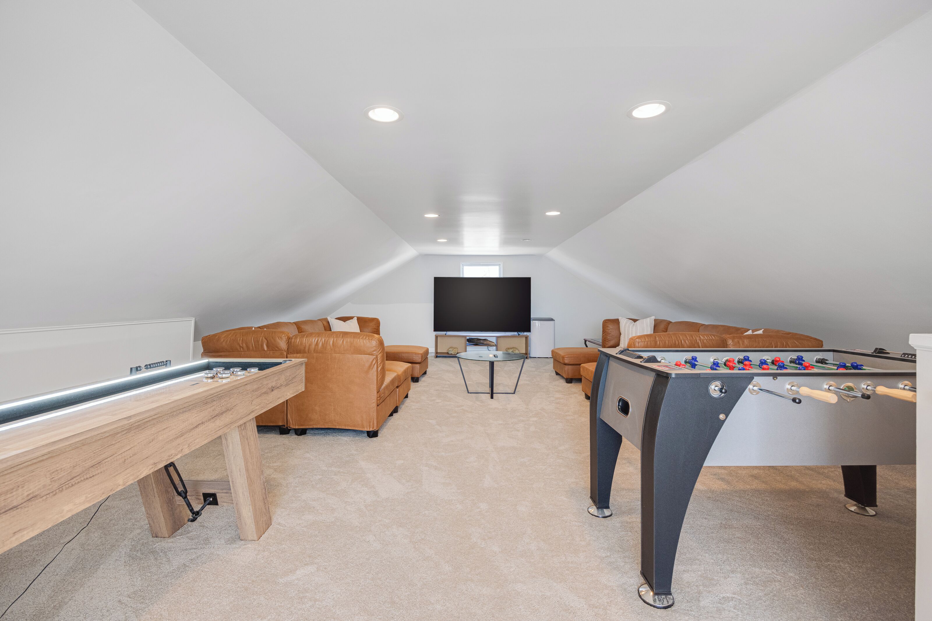 Ein Dachzimmer mit Tischfußball, Billardtisch und Flachbildfernseher.