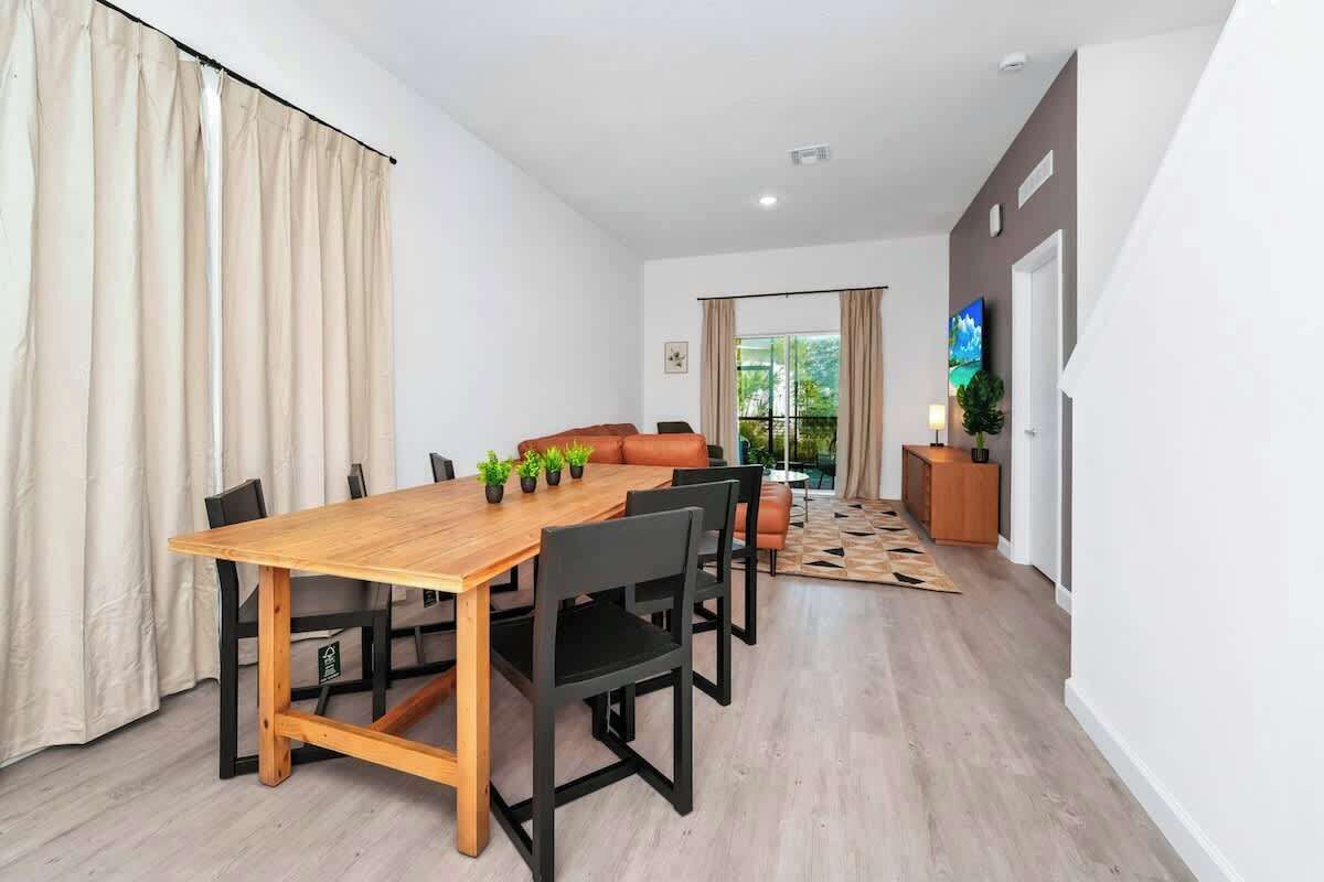 Een moderne eethoek met een houten tafel, zwarte stoelen, een bank en een klein kastje.