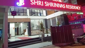 Esterno dell'Hotel Shri Shrinivas Residency, con un'insegna ben visibile, un ingresso sorvegliato e una scala che conduce all'entrata.