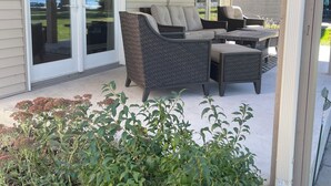 A covered patio with a wicker sofa, a decorative sun wall, and a view of a lake.