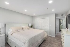 A bedroom with a bed, nightstands, a dresser, and a closet.