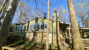 Een chalet met een gevel van natuursteen, grote ramen en een schoorsteen.