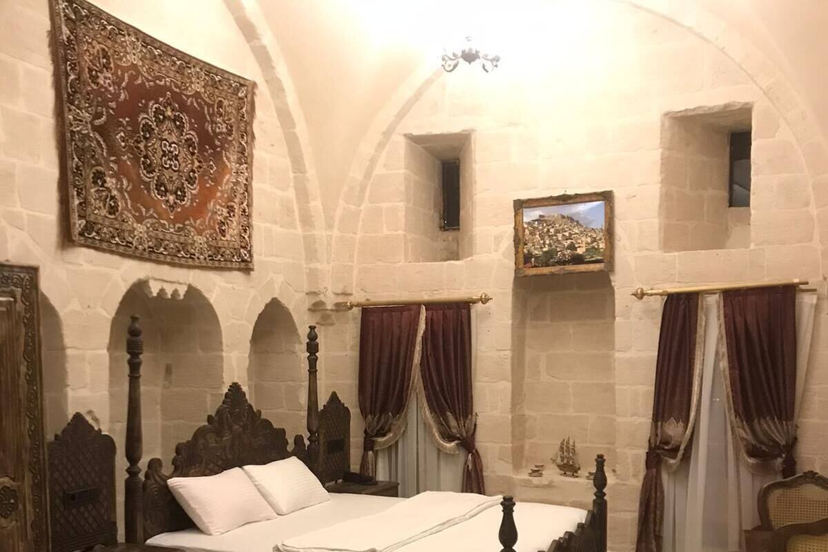 Ein Schlafzimmer mit einem großen Bett, einem Holz-Kopfteil, einem dekorativen Teppich und einem Bild an der Wand.