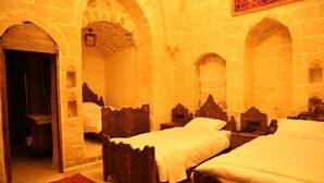 A room with two wooden beds, stone walls, and a red carpet. - Kasim Efendi Konagi (Mardin)