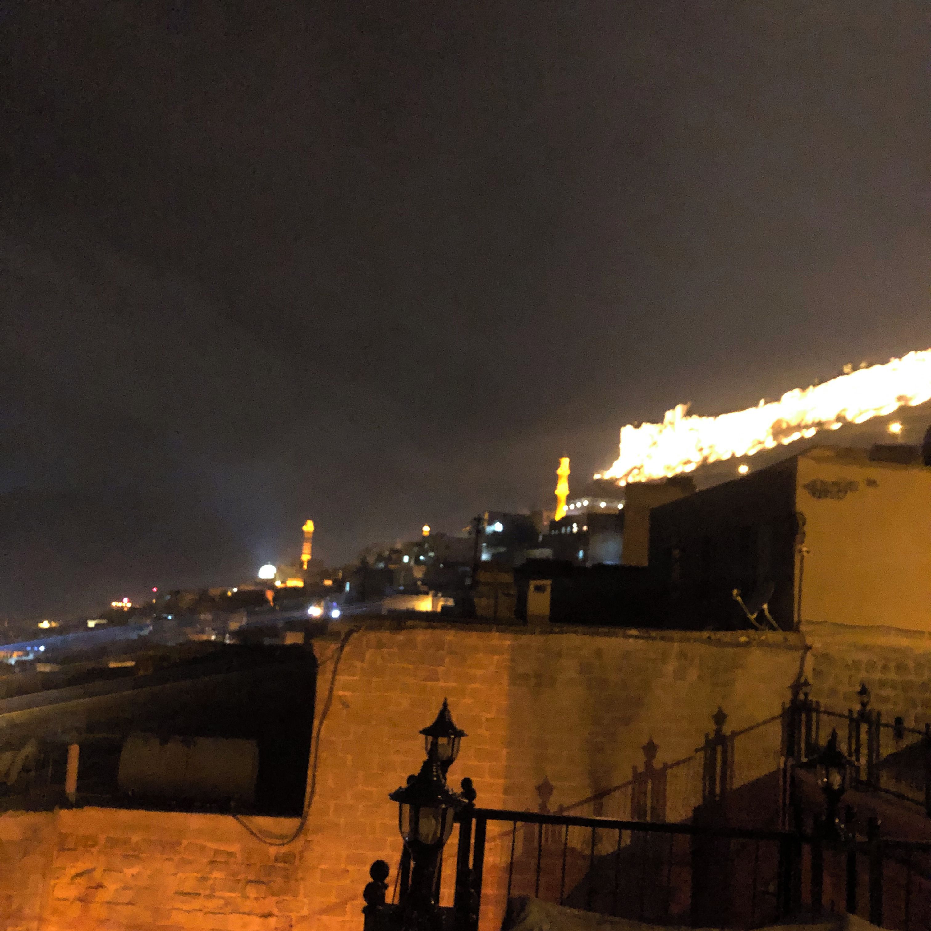 Ein Nachtblick auf eine Stadtlandschaft mit beleuchteten Gebäuden und einem markanten Turm.