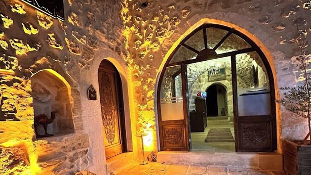 An arched stone entrance with a stone floor, illuminated by warm lighting. - Kasim Efendi Konagi (Mardin)