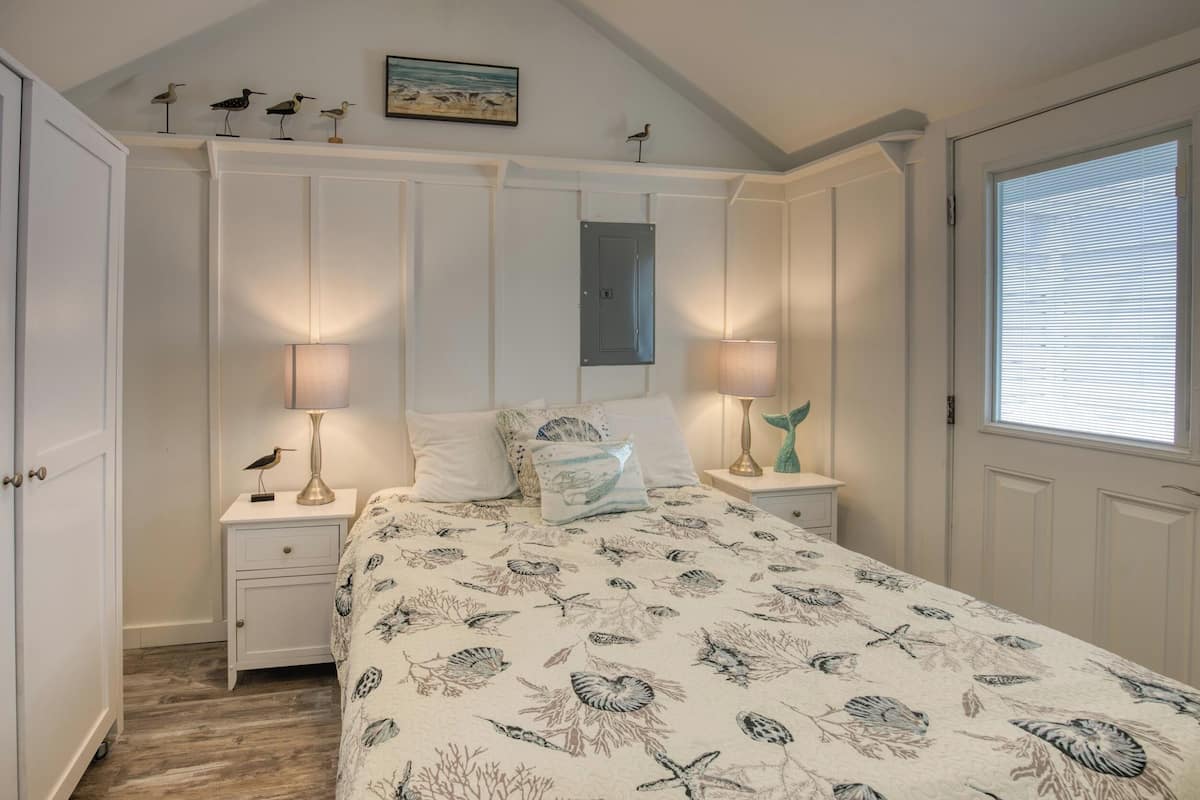 A bedroom with a bed, nightstands, a dresser, and a window with blinds.