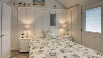 A bedroom with a bed, nightstands, a dresser, and a window with blinds.