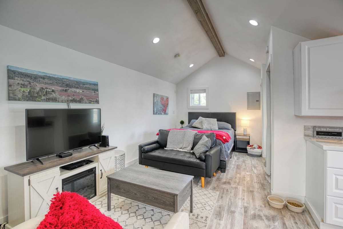 A modern living room with a flat-screen TV, a fireplace, a sofa, and a dining area.