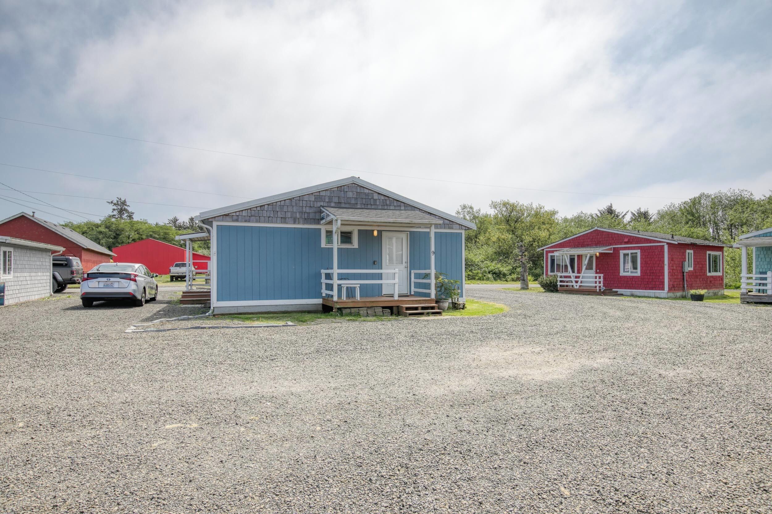 A small, single-story building with a porch and a gravel driveway.