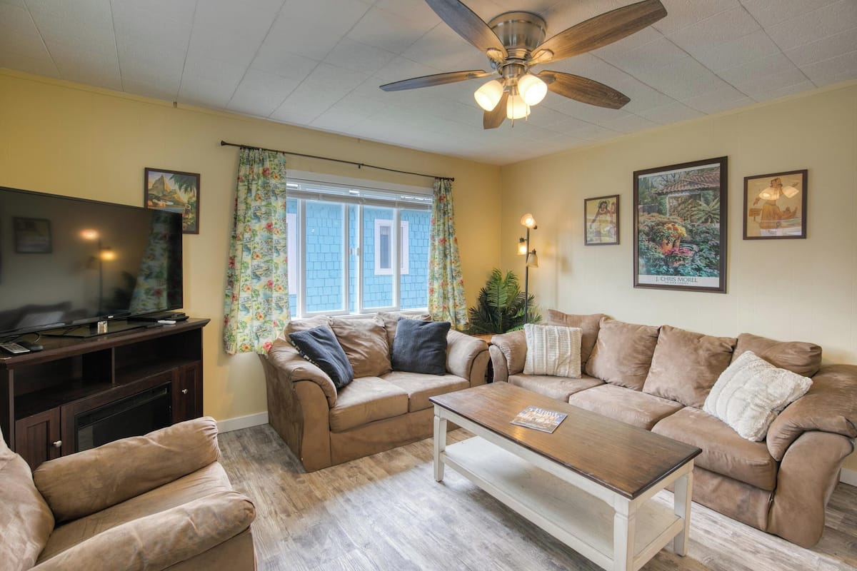 A living room with a ceiling fan, a television on a stand, a sofa set, and a coffee table.