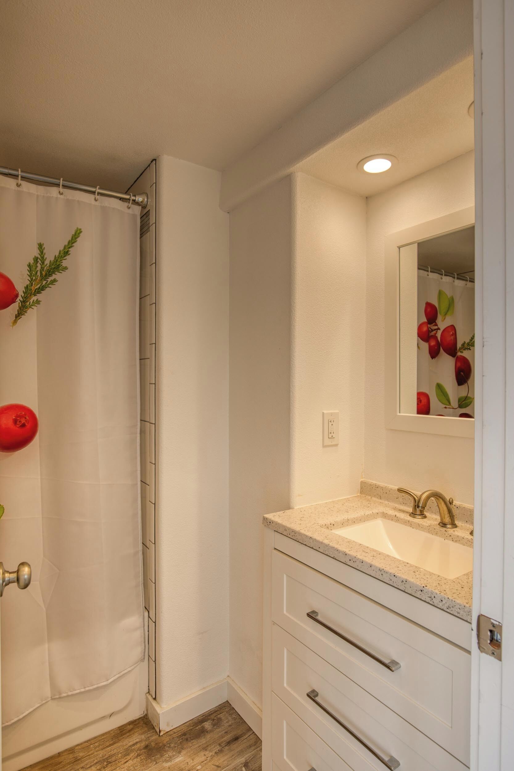 A bathroom with a shower curtain, a sink with a mirror, and a door with a handle.
