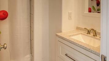 A bathroom with a shower curtain, a sink with a mirror, and a door with a handle.