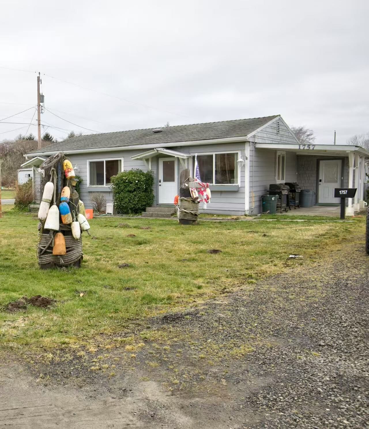 A house with a front porch, a mailbox, and a grassy yard.