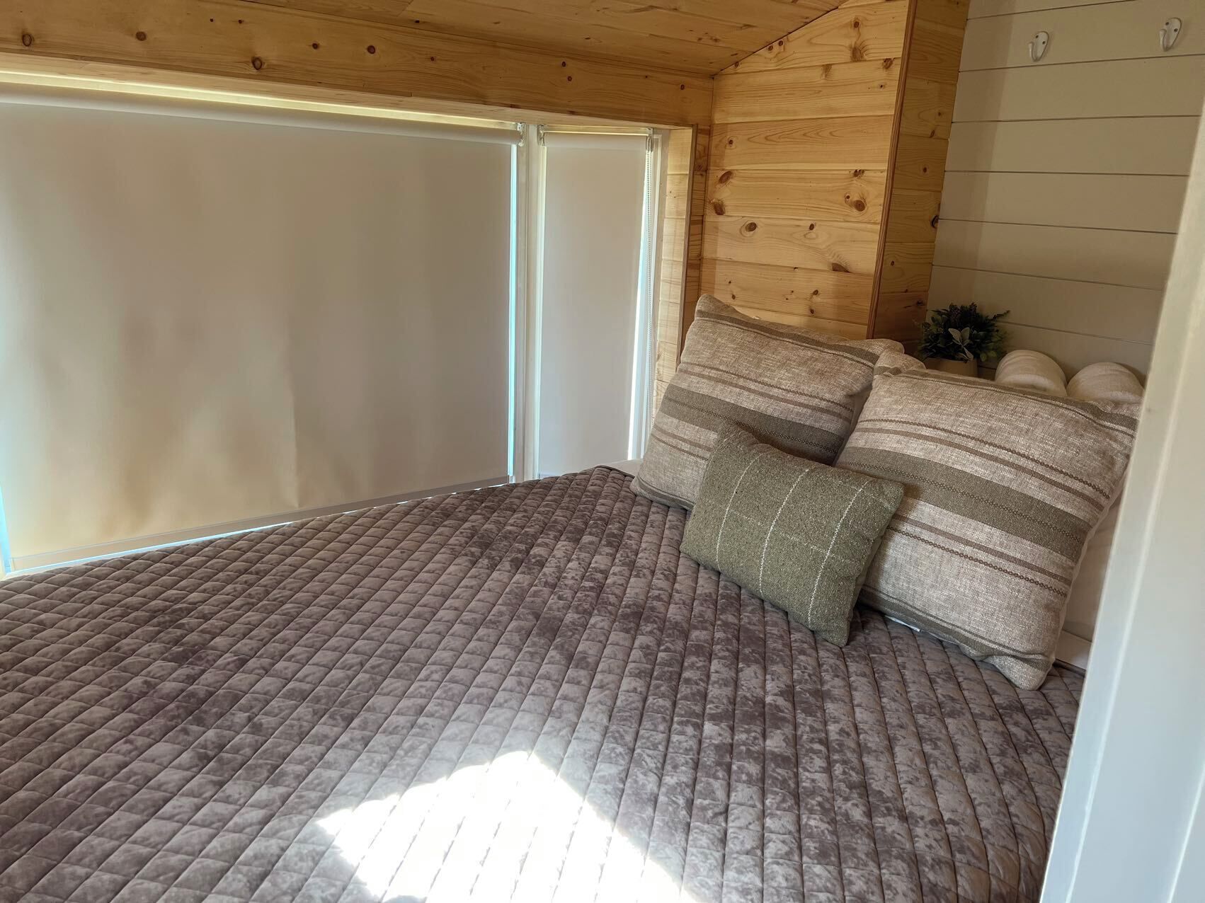 Ein Zimmer mit einem Bett, einem Fenster und einer Holzbalkendecke.