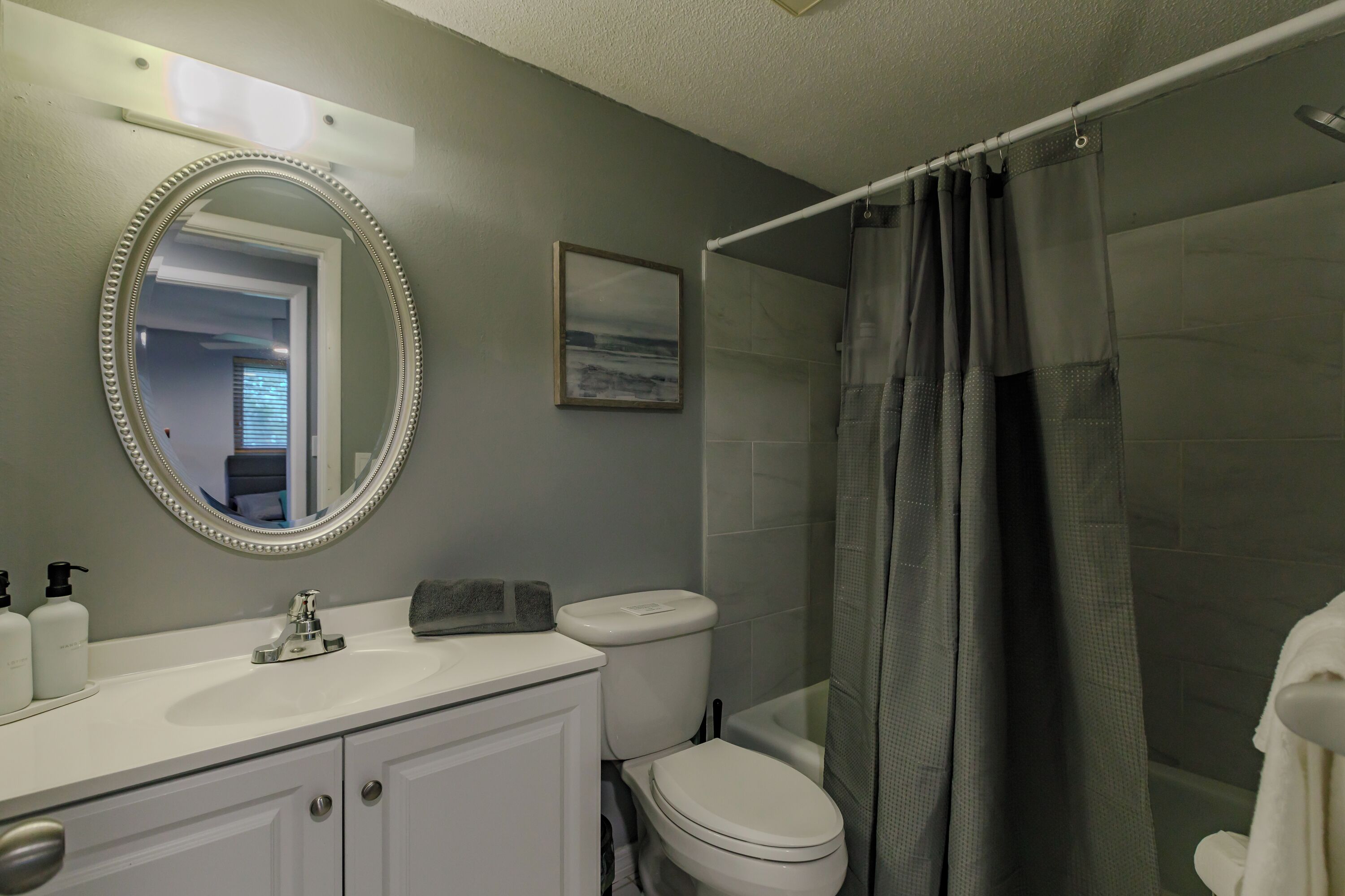 A bathroom with a white sink, a mirror, a toilet, and a shower curtain.