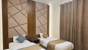 A hotel room with two beds, a wooden headboard, a nightstand, and a window with curtains. - Lordy Serviced Apartments (Riyadh)