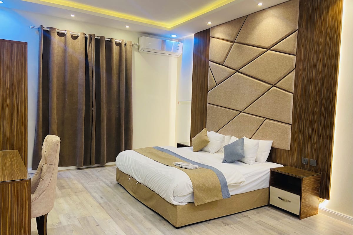 Une chambre moderne avec un grand lit, une table de chevet, une chaise et un appareil de climatisation.