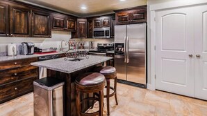 A kitchen with dark wooden cabinets, stainless steel appliances, a granite countertop, and a bar stool area. - 30% OFF PROMO! East Ogden Dream, Newly Built, BBQ, Patio, Views, Dedicated Spa! (Ogden)