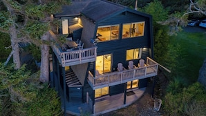 Een chalet met twee verdiepingen, een balkon, grote ramen en een terras.