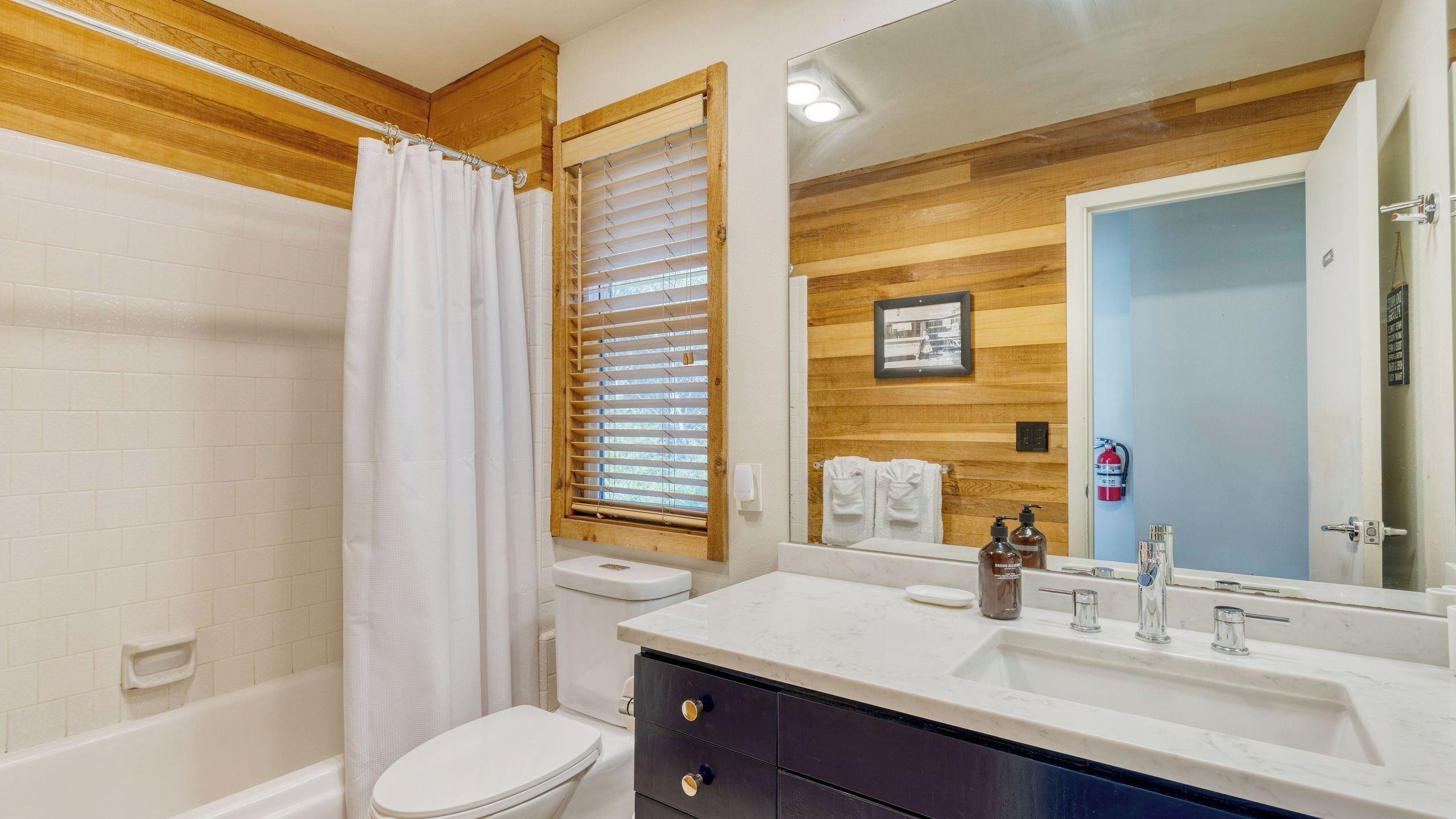 Un baño con ducha, inodoro, lavabo y espejo.