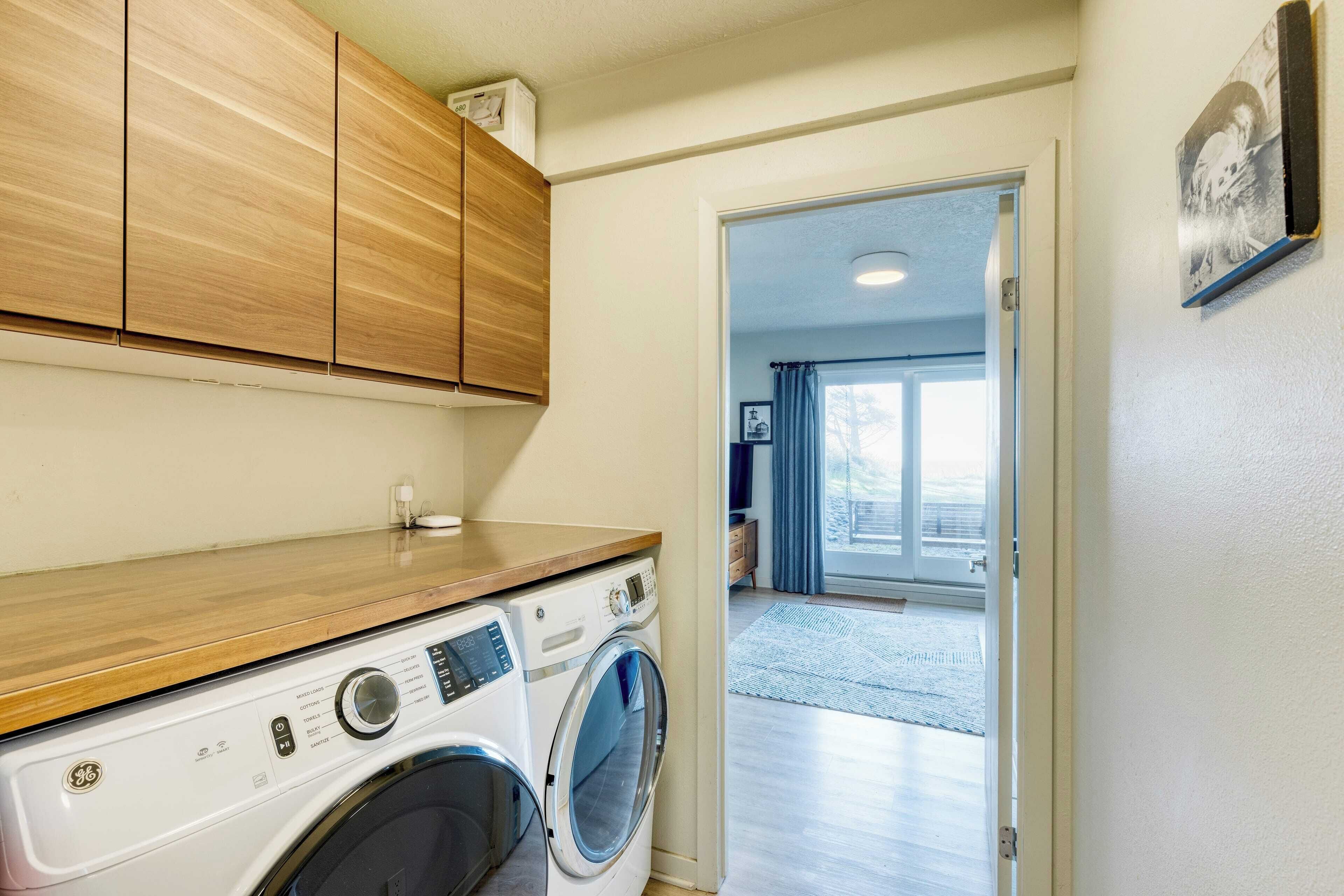 A laundry area with a washing machine and wooden cabinets.